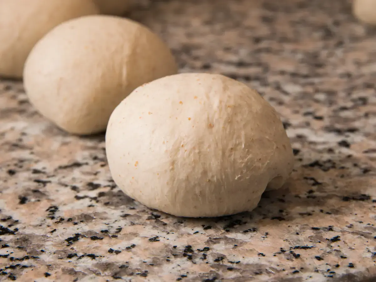 Panetti di impasto allineati sul banco di lavoro, infarinati